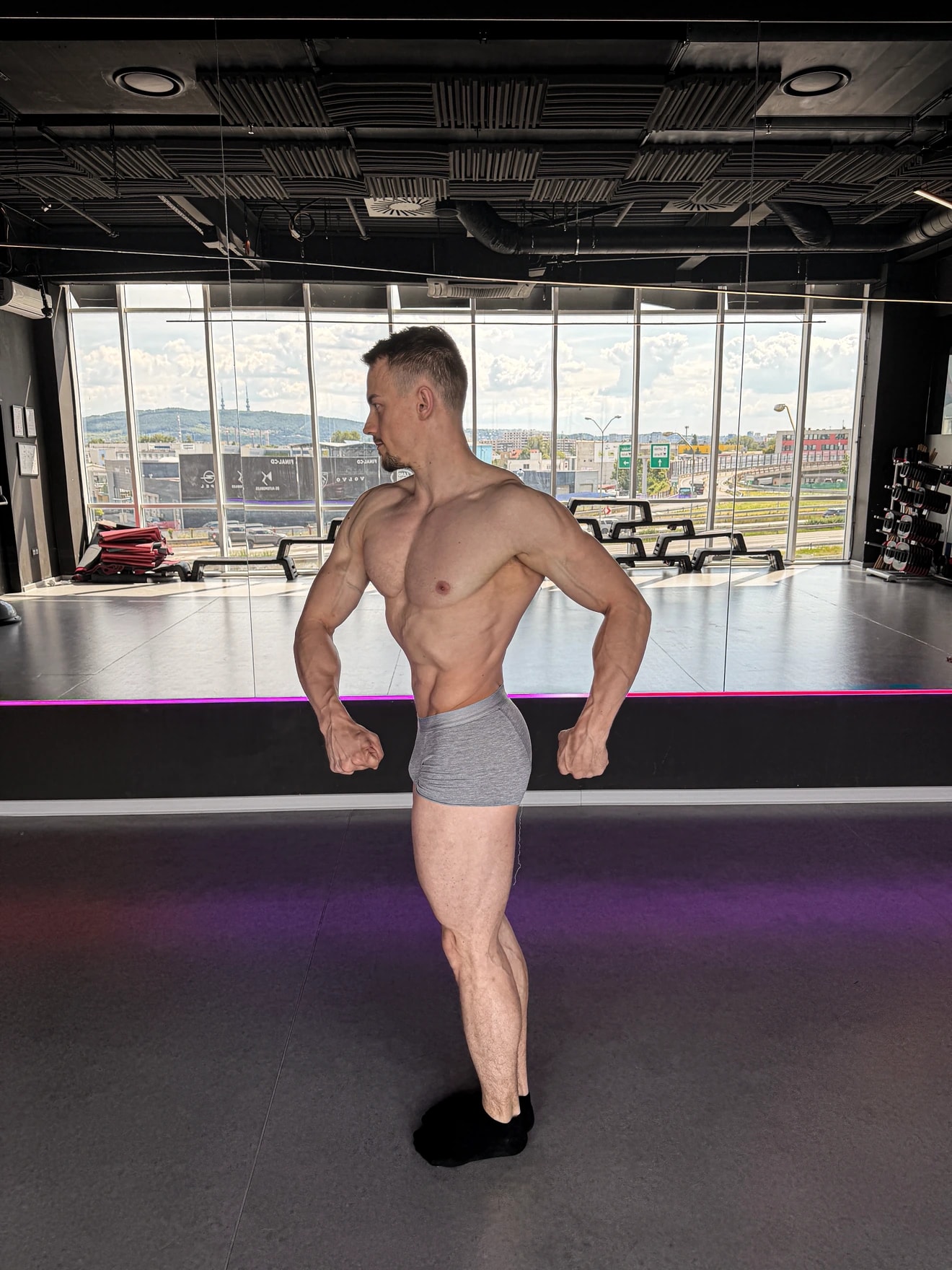 Nácvik pózovania Classic Physique v sále pred zrkadlom